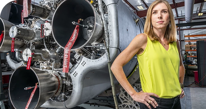 NI employee in front of a launch vehicle engine inside a factory