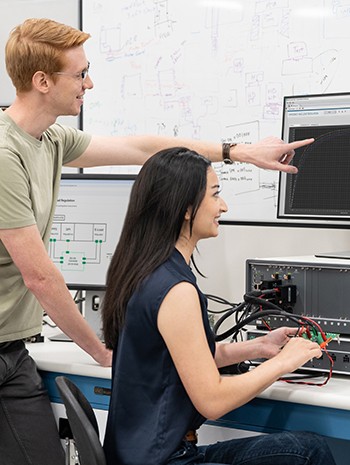 An image of two engineering students looking at a computer monitor in a teaching lab setting​