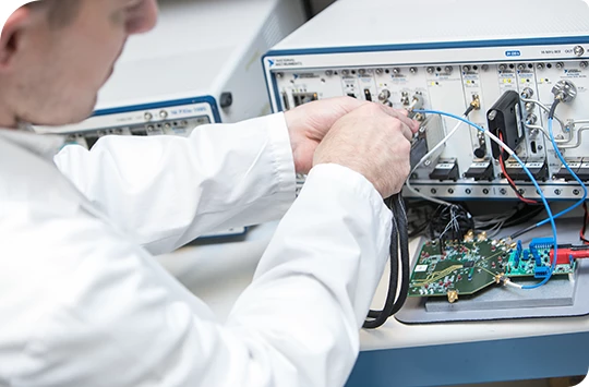 Lab technician testing circuit board connected to test equipment