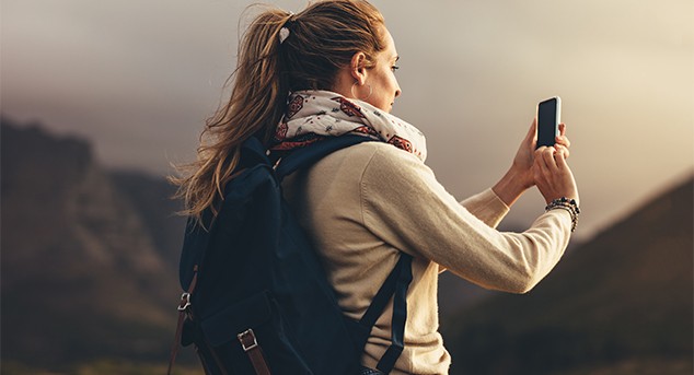 A woman uses her cell phone to locate her position while hiking in the mountains