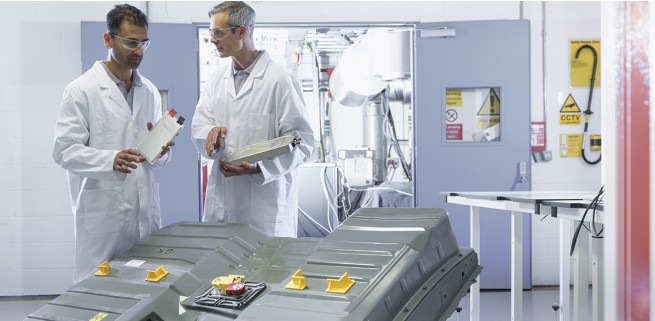 Two engineers discuss test setup in an EV production lab.