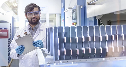 Hombre mira el paquete de celdas de batería en un laboratorio de pruebas.