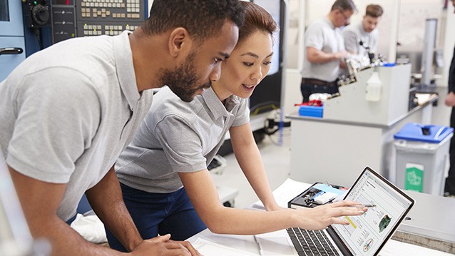 Ein Ingenieur und ein Ingenieur besprechen ein Motorsimulationsmodul als Teil eines HIL-Tests, das auf einem VeriStand-Frontpanel angezeigt wird.