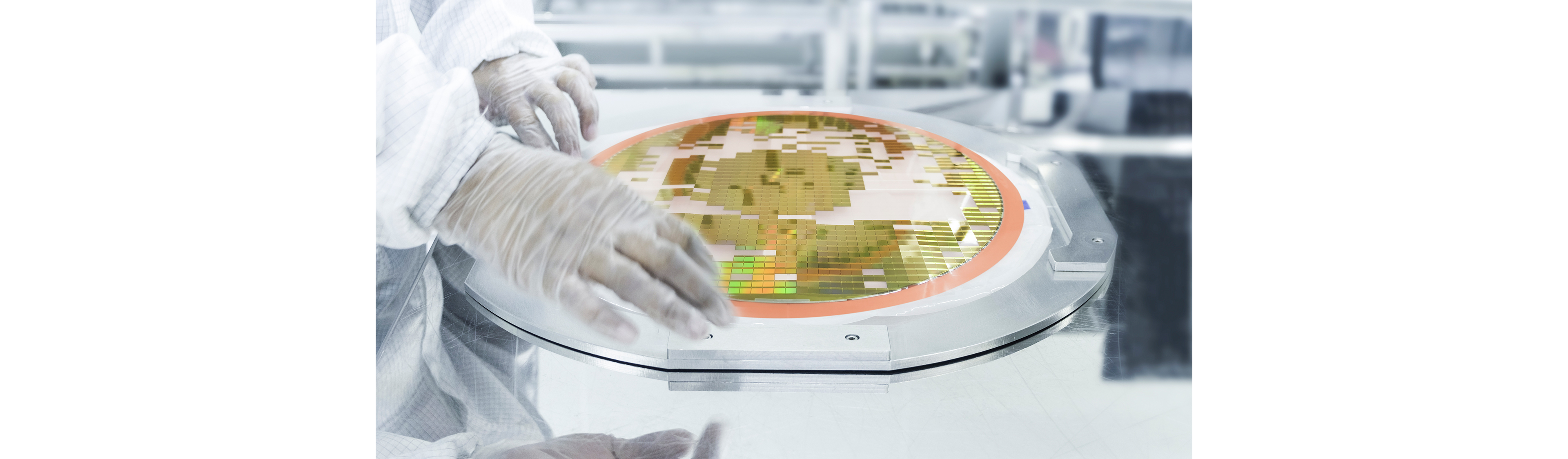 Technicien manipulant un wafer semi-conducteur sur un équipement d’inspection, montrant des matrices à motifs utilisées pour l’analyse du rendement et des défauts dans la fabrication.