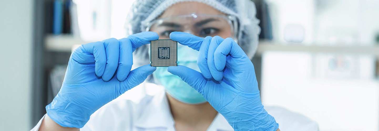 Technicien de laboratoire inspectant un circuit intégré (CI) à semi-conducteurs.