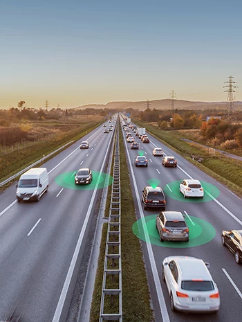 Des véhicules autonomes en train de rouler aux côtés d’autres voitures sur une autoroute à quatre voies au coucher du soleil