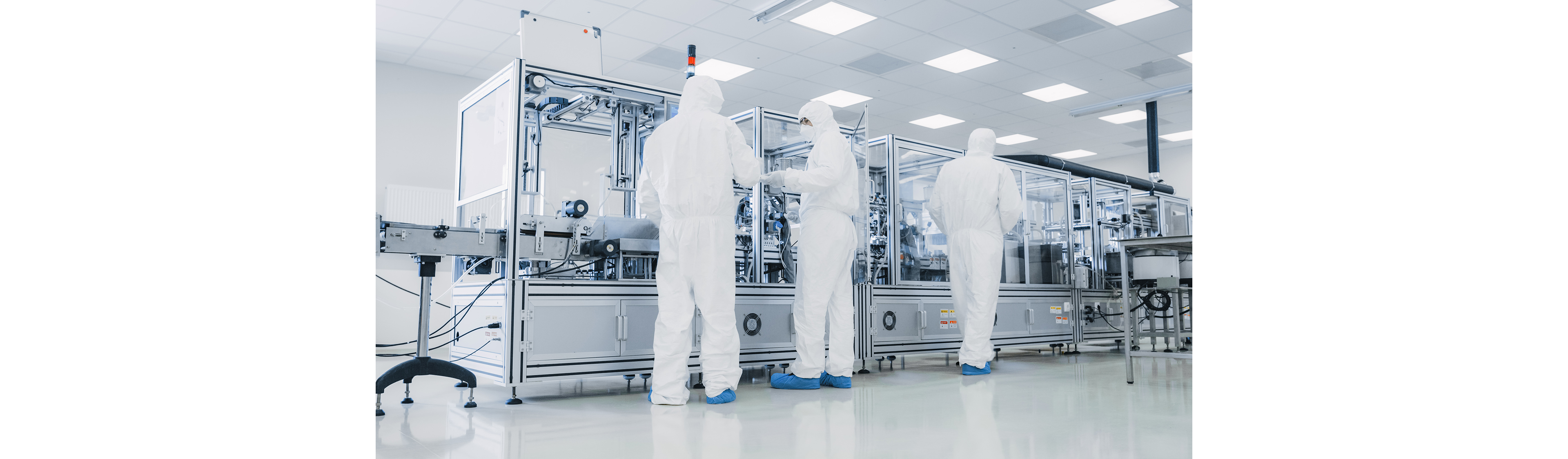Ligne de fabrication en salle blanche avec plusieurs techniciens surveillant l’équipement de production automatisé de semi-conducteurs pour la cohérence et le contrôle de qualité.