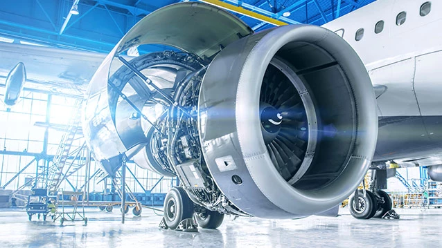 An aerospace engineer stands in front of an airplane in a hangar