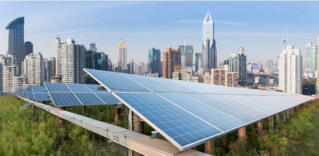 Large grid of solar panels in front of a city skyline.