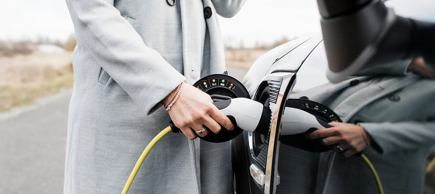 A driver charges her electric vehicle on the side of the road.