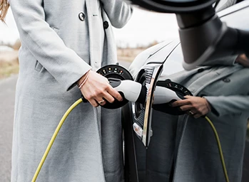 A driver charges her electric vehicle on the side of the road.