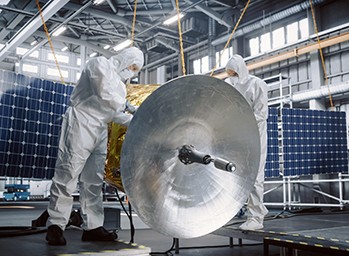 deux ingénieurs en combinaison spatiale testant le matériel d’un satellite