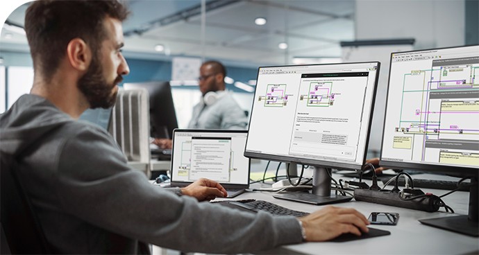 An engineering student looking at computer monitors displaying NI LabVIEW software