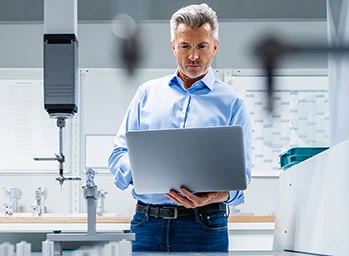 Engineer with laptop at automated manufacturing machinery in industry