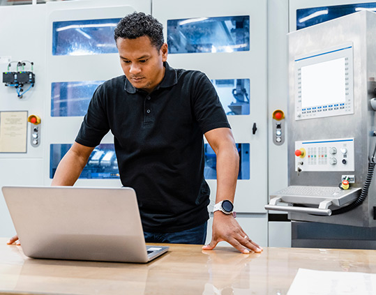 Maintenance engineer looking at laptop in automated factory