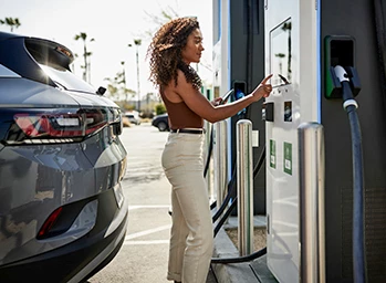 Mujer en una estación de carga de vehículos eléctricos