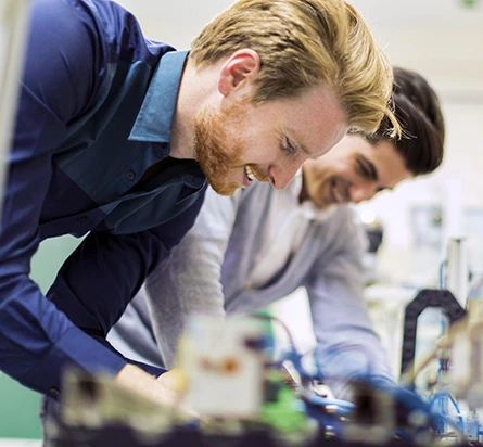 Dos técnicos de laboratorio que trabajan de forma interactiva en un DUT en un banco de pruebas