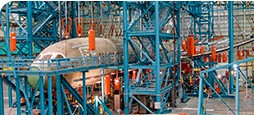 Aircraft undergoing static and structural testing in a hangar next to scaffolding