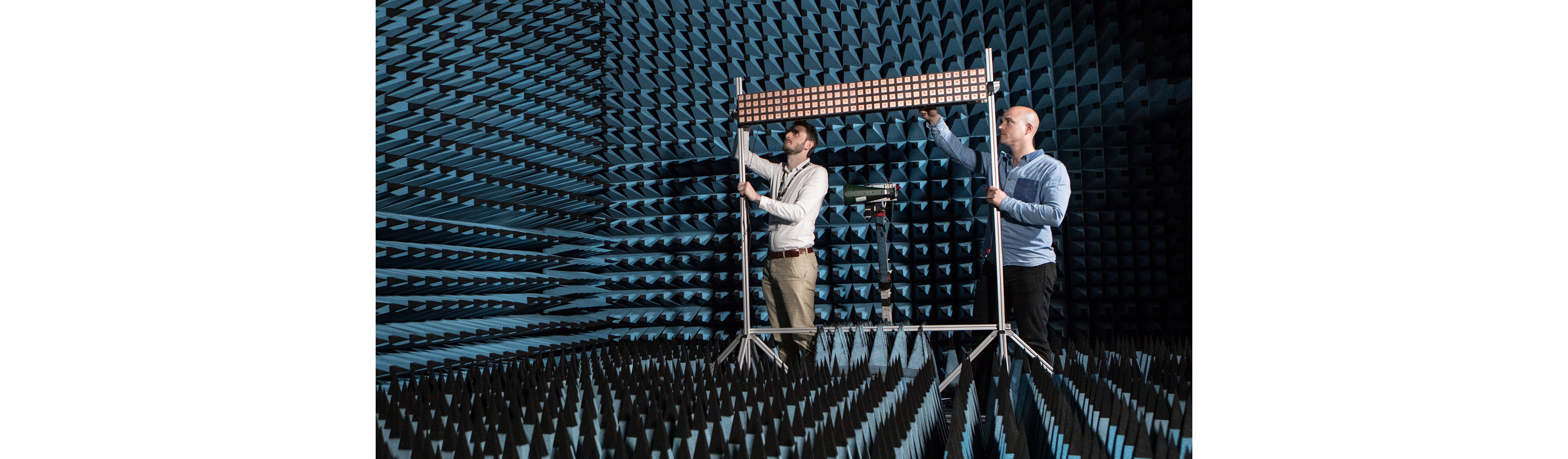 Ingenieros que realizan pruebas de señales inalámbricas conformes a las normas en una cámara anecoica utilizando instrumentación avanzada de medición de RF.