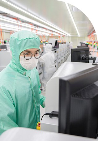 방진복을 입은 엔지니어가 복잡한 생산 현장에서 miniLED 테스터를 작동하고 있습니다.