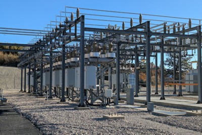 Electrical grid substation with industrial circuit breakers and cabinets for monitoring and control hardware.​