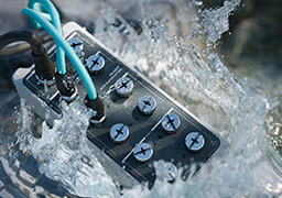 A rugged, IP65/IP67 rated FieldDAQ device is dropped in a puddle of water