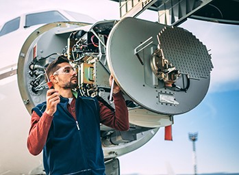technicien d’aéronef travaillant sur des équipements radar dans le nez d’un avion