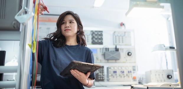 A test engineer records failure data on her tablet in a laboratory.