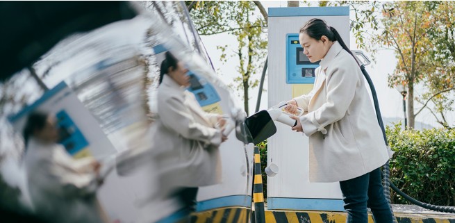 Woman charging EV at a public charging station