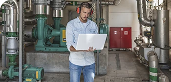 Ingenieur, der den Zustand von Fertigungsanlagen auf seinem Laptop überwacht