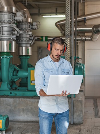 engineer using laptop in industrial facility