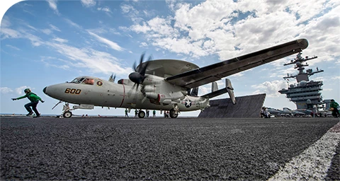 military plane with radome preparing to take off from aircraft carrier