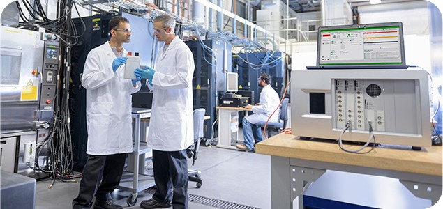 Two engineers wearing safety equipment in a lab surrounded by power cables and machinery
