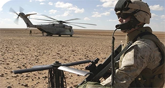 Soldat in der Wüste mit einem Hubschrauber im Hintergrund