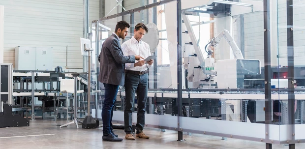 Two engineers look at data on a tablet together in a modern lab.