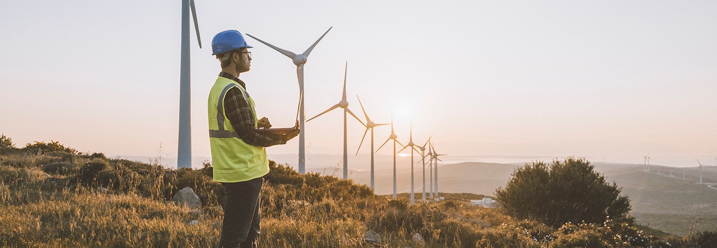 engineer on top of a mountain monitoring wind turbines