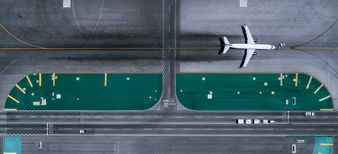 A commercial airliner taxis around an oblong stretch of runway.