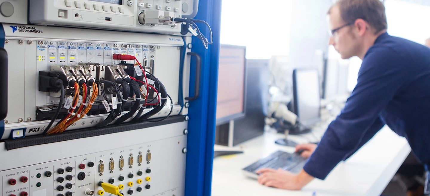 Several PXI chassis running HIL simulations and an engineer working on the computer to start running the simulations