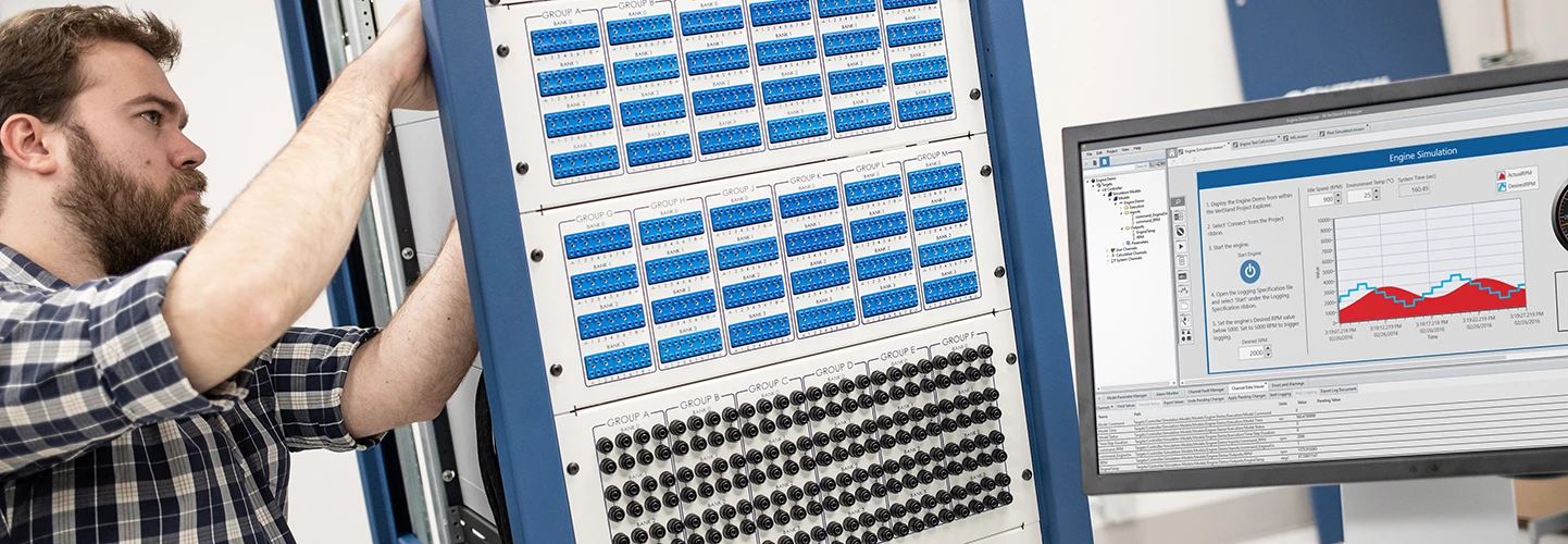 ingeniero ajusta la configuración de hardware-in-the-loop y una pantalla muestra los resultados de la simulación del motor