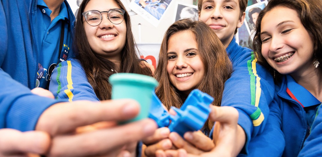 Three students holding CosmoCup menstrual collector at FIRST competition