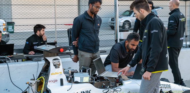 Team on laptops preparing their autonomous race car for competition