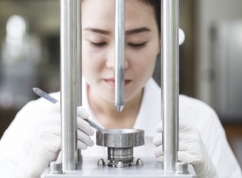 A woman wearing a white shirt performs a test on a 5G semiconductor