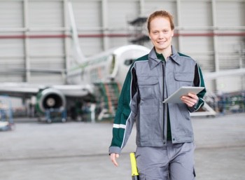 An aerospace engineer stands in front of an airplane in a hangar