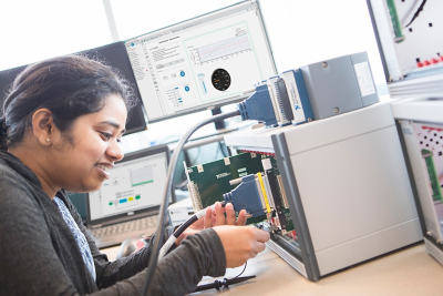 An engineer inserts a SLSC module into an SLSC chassis on a desk near her test station. 