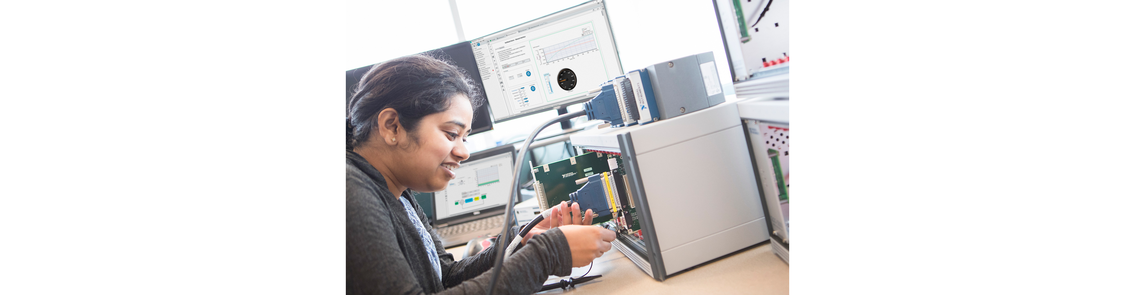 An engineer inserts a SLSC module into an SLSC chassis on a desk near her test station. 