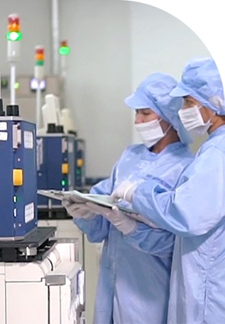 방진복을 입은 엔지니어가 NI STS가 전경에 배치된 반도체 생산 테스트 셀을 모니터링합니다.