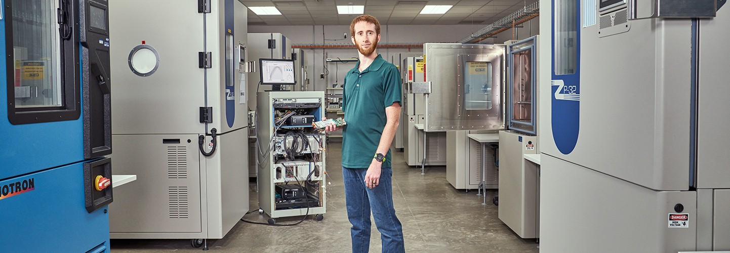 Engineer standing in thermal lab holding an electronic circuit board 