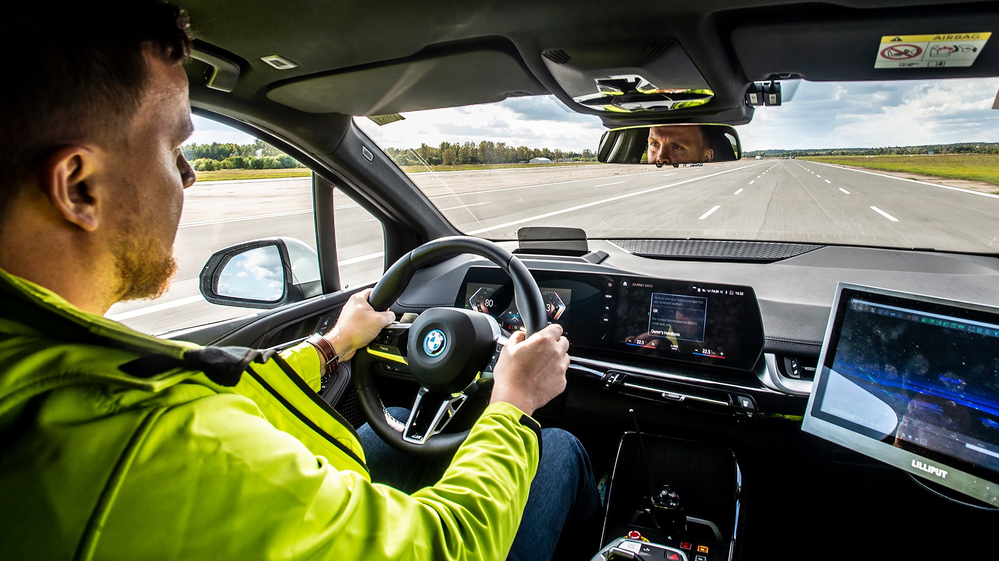 Automotive test driver operates a vehicle on a test track while monitoring ADAS validation software displayed on in-vehicle screens.