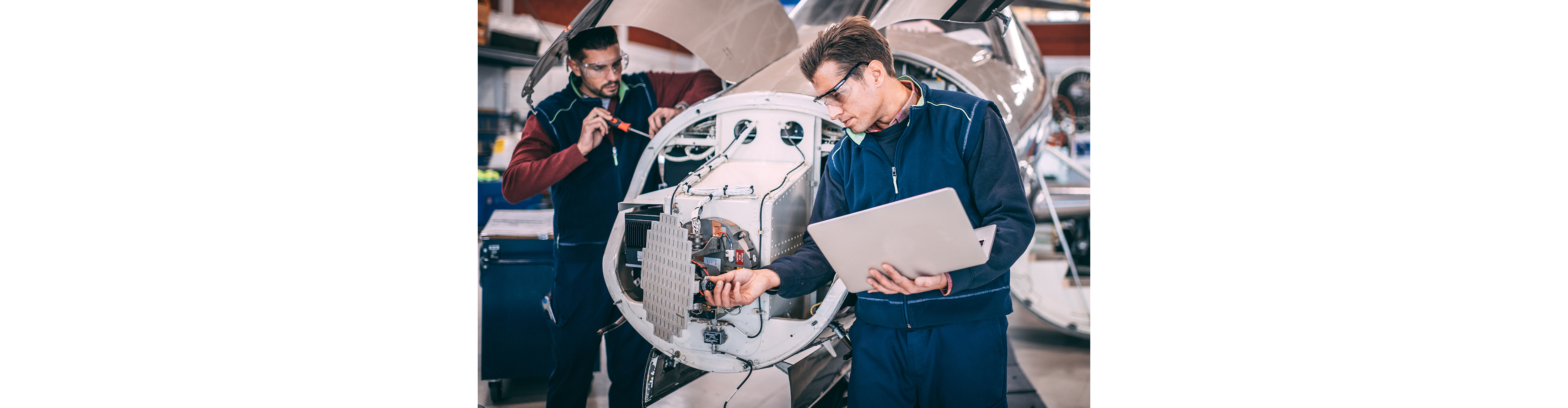 Two engineers perform an inspection and operational test of an aircraft engine and avionics sensor cluster.